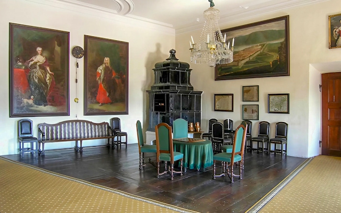 Cesky Krumlov castle room with paintings, chandelier, and antique furniture.