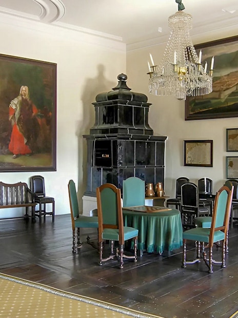 Cesky Krumlov castle room with paintings, chandelier, and antique furniture.