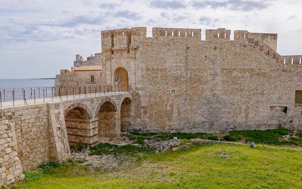 Maniace Castle stone walls and arched bridge in Syracuse, Italy.