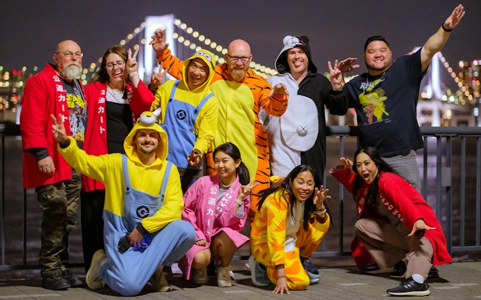 Group in costumes enjoying Asakusa Tour with Rainbow Bridge in background.