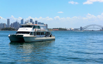 Luxury yacht on Sydney Harbour with city skyline and Harbour Bridge in the background.