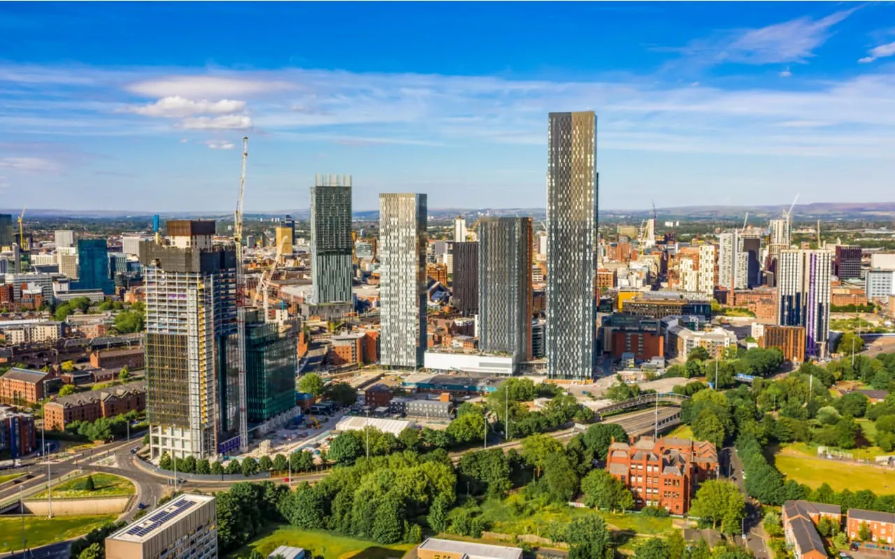 Manchester skyline with modern skyscrapers and green spaces, viewed from above.