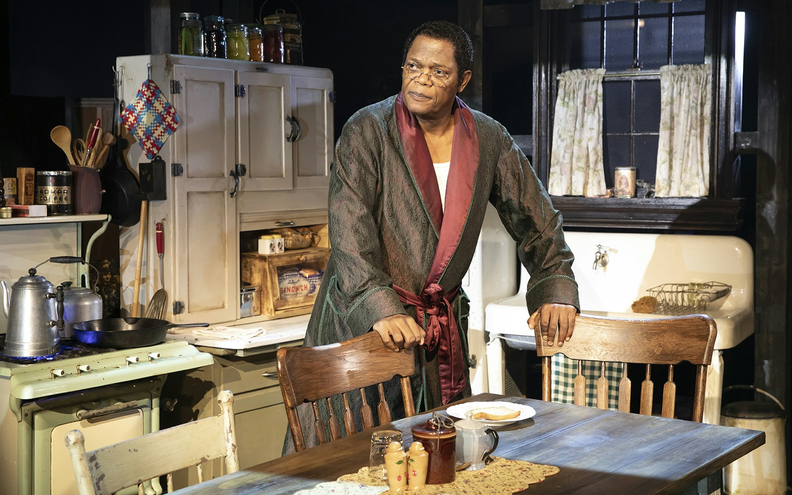 Man in a robe stands in a vintage kitchen setting from "The Piano Lesson" play.
