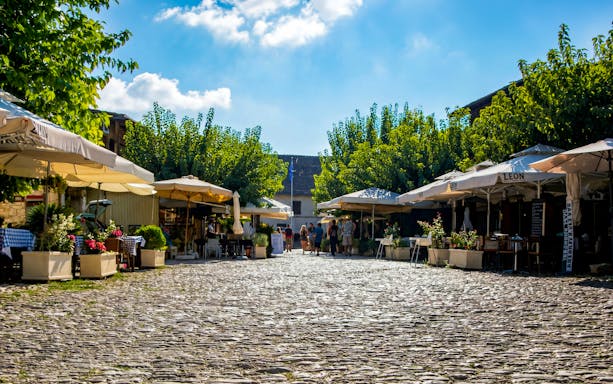 Cobblestone street in Omodos village with outdoor cafes and people strolling.
