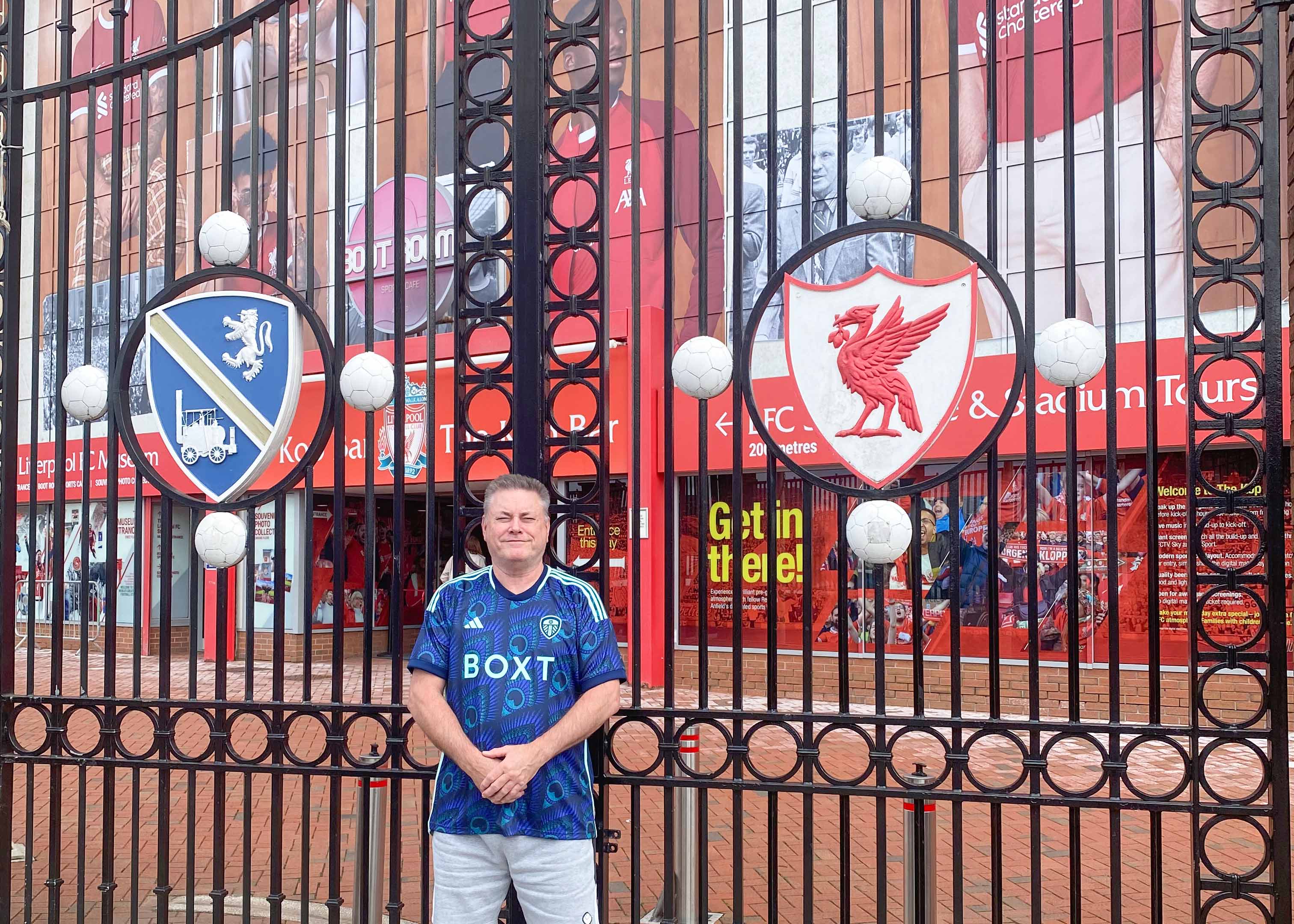 Shankly Gates at Liverpool FC stadium entrance, featuring iconic "You'll Never Walk Alone" sign.
