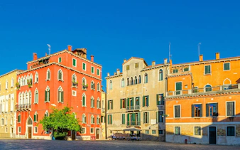 Colorful Venetian buildings in a sunny square, part of the Venice Holy Heist exploration game.