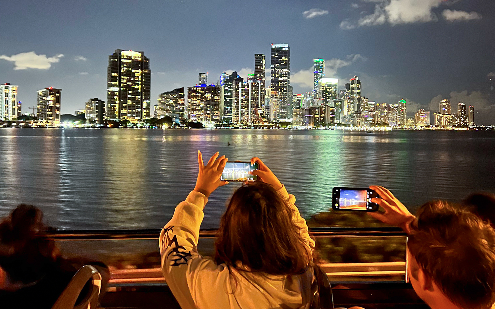 Passengers capturing Miami's illuminated skyline from the Big Bus Miami Panoramic Night Tour.