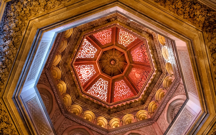 Ornate ceiling of Monserrate Palace with intricate patterns and warm lighting.