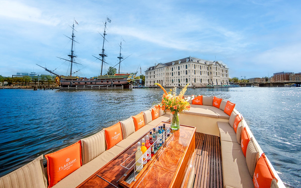 Luxury open boat cruise in Amsterdam with view of the National Maritime Museum and historic ship.