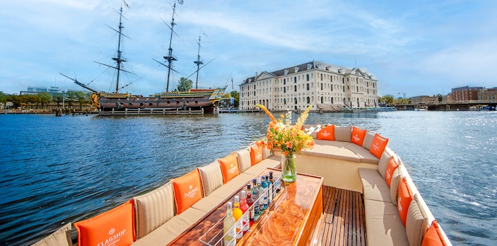 Luxury open boat cruise in Amsterdam with view of the National Maritime Museum and historic ship.