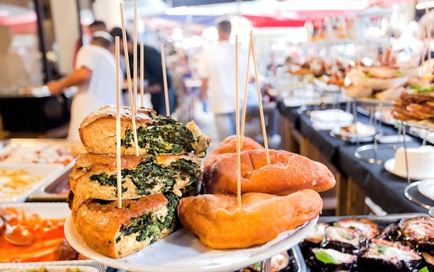 Gourmet street food display with spinach pastries in Rome market.