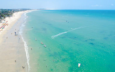 Cumbuco beach with kitesurfers and boats on turquoise water, Sao Paulo coastal adventure.