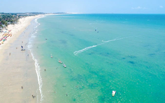 Cumbuco beach with kitesurfers and boats on turquoise water, Sao Paulo coastal adventure.