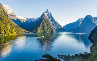 Cruise ship in Milford Sound fjords, New Zealand, with tourists enjoying canapes and champagne.