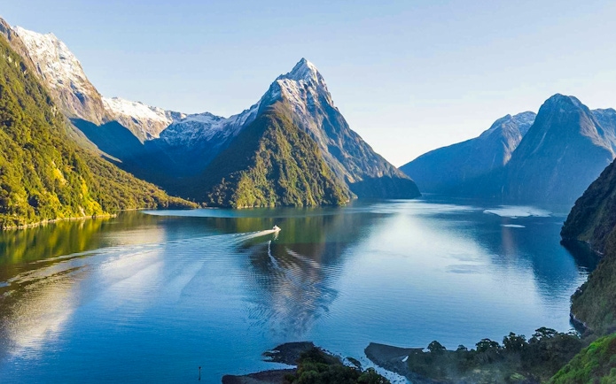 Cruise ship in Milford Sound fjords, New Zealand, with tourists enjoying canapes and champagne.