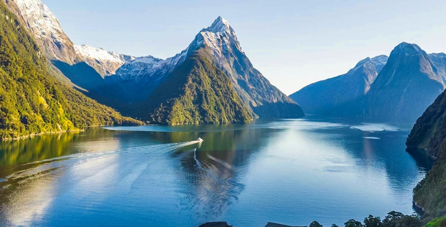 Cruise ship in Milford Sound fjords, New Zealand, with tourists enjoying canapes and champagne.