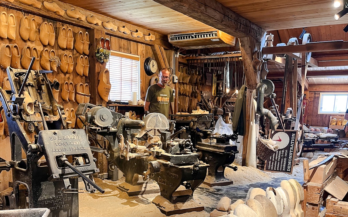 Clog making factory with traditional machinery and wooden clogs on display.