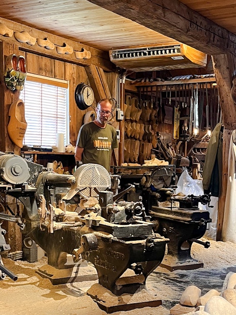 Clog making factory with traditional machinery and wooden clogs on display.