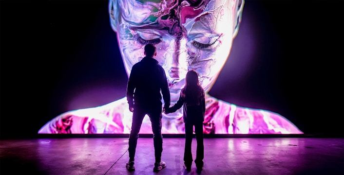 Visitors at AMAZE Amsterdam viewing a vibrant digital art display.