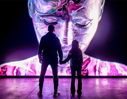 Visitors at AMAZE Amsterdam viewing a vibrant digital art display.