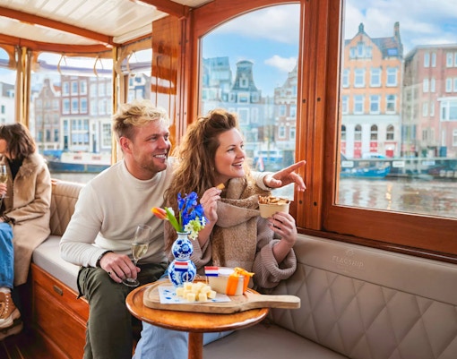 Couple enjoying a luxury romantic cruise in Amsterdam with city views.