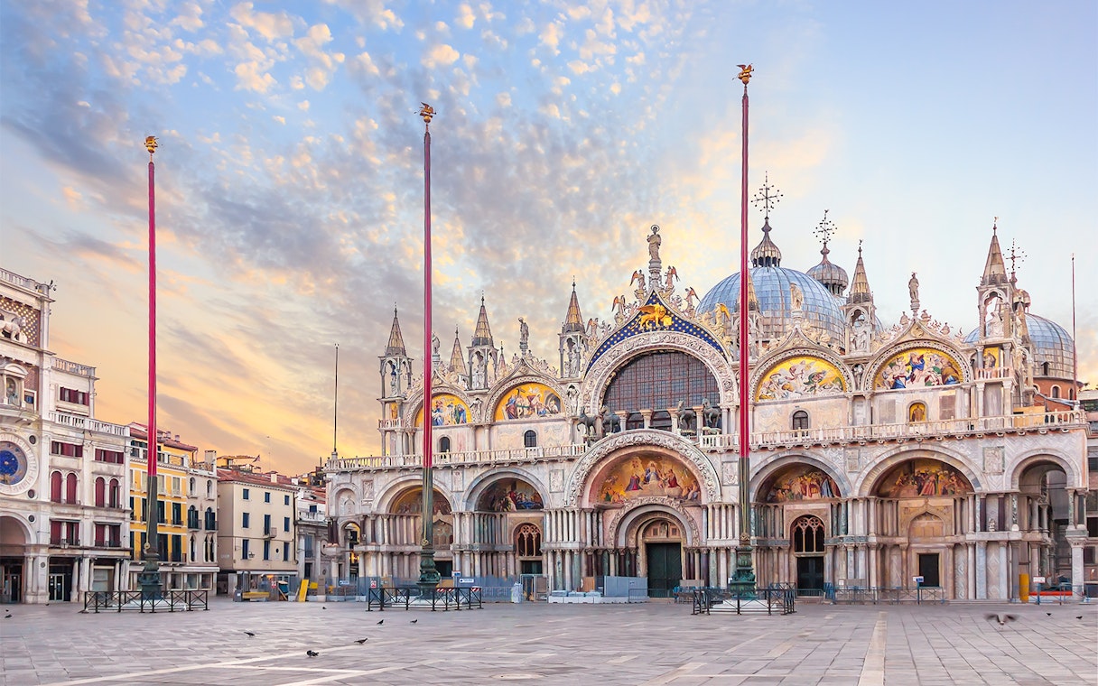 St. Mark's Basilica facade at sunrise in Venice, Italy, showcasing intricate mosaics and architecture.
