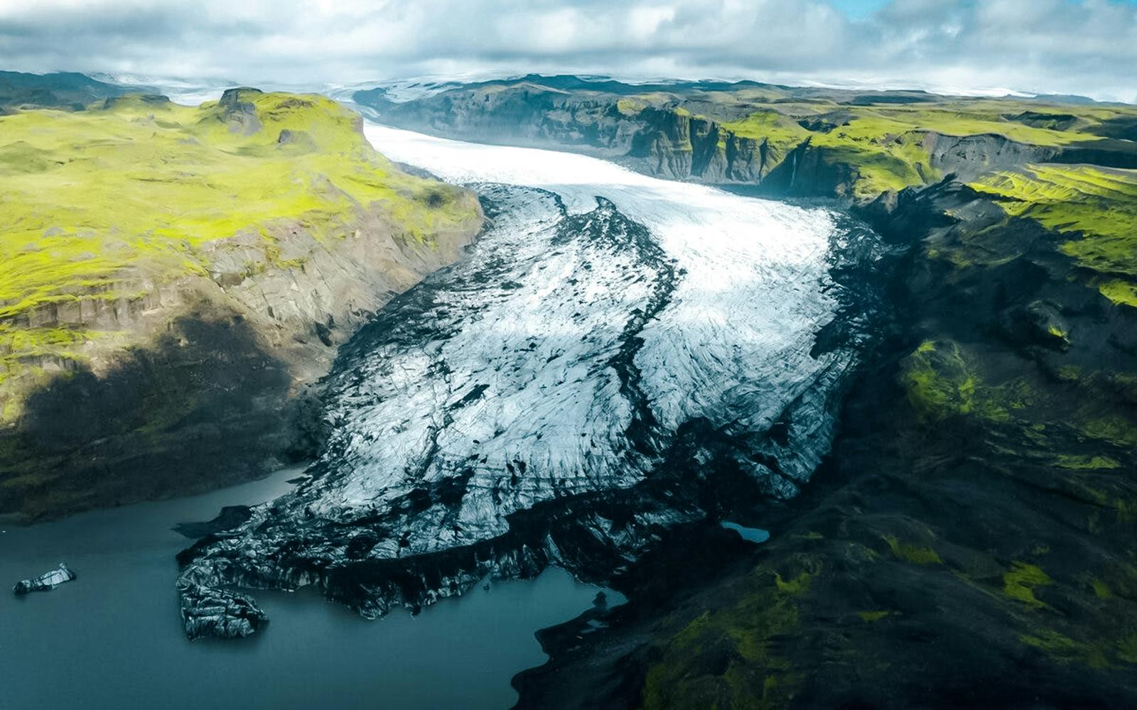 Sólheimajökull glacier with surrounding green hills and icy landscape in Iceland.