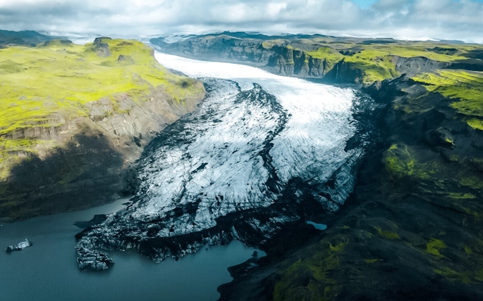 Sólheimajökull glacier with surrounding green hills and icy landscape in Iceland.