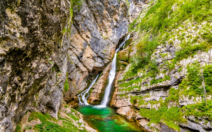 Slap Savica Waterfall cascading down rocky cliffs into a turquoise pool in Slovenia.