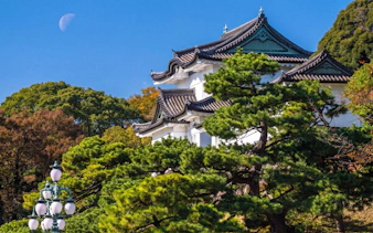 Tokyo Imperial Palace with traditional architecture and surrounding trees under a clear sky.