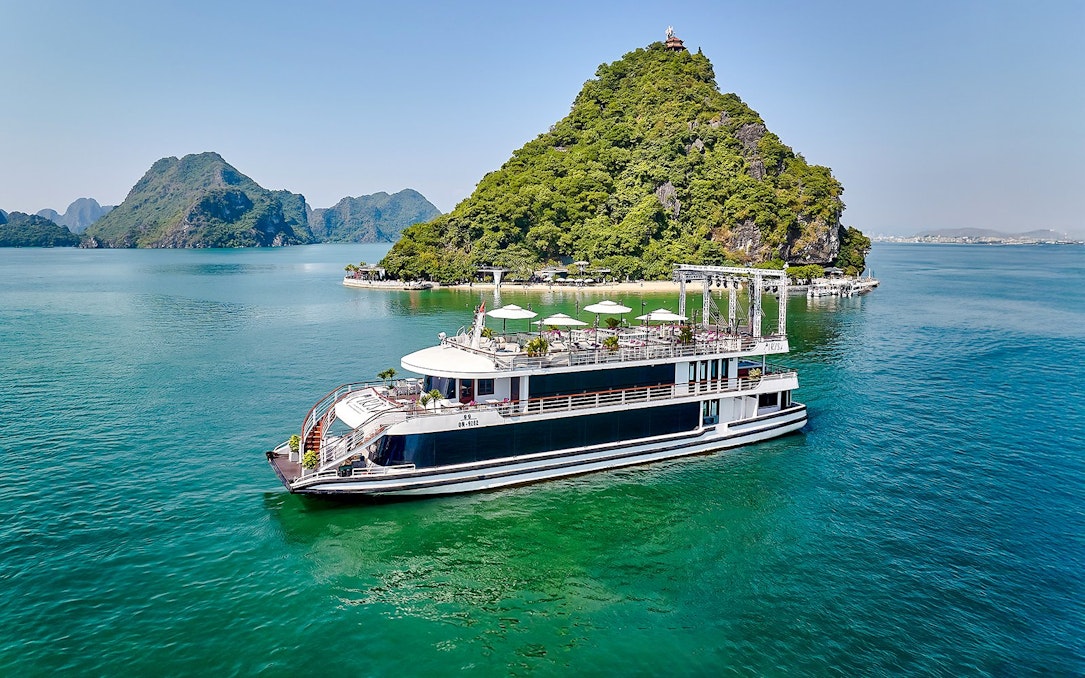 Luxury cruise ship sailing in Ha Long Bay with limestone islands in the background.