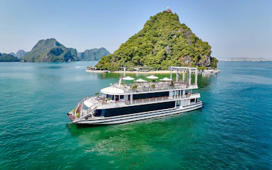 Luxury cruise ship sailing in Ha Long Bay with limestone islands in the background.