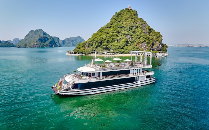 Luxury cruise ship sailing in Ha Long Bay with limestone islands in the background.