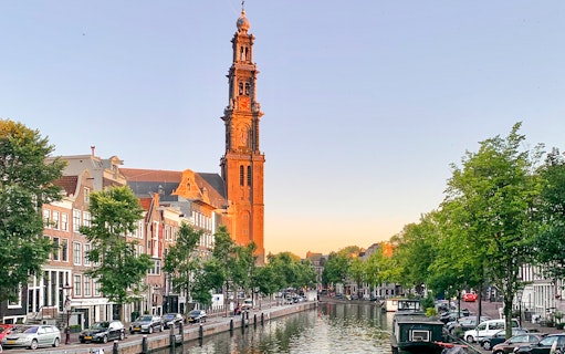 Westerkerk tower overlooking Amsterdam canal at sunset.