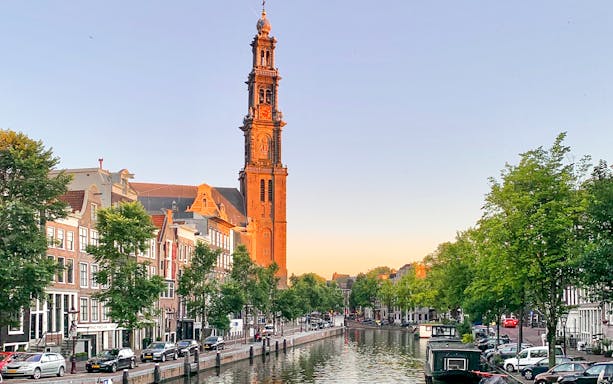 Westerkerk tower overlooking Amsterdam canal at sunset.