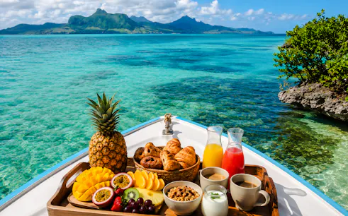 Brunch spread on a boat with tropical fruits and drinks, Mahebourg lagoon, Mauritius.