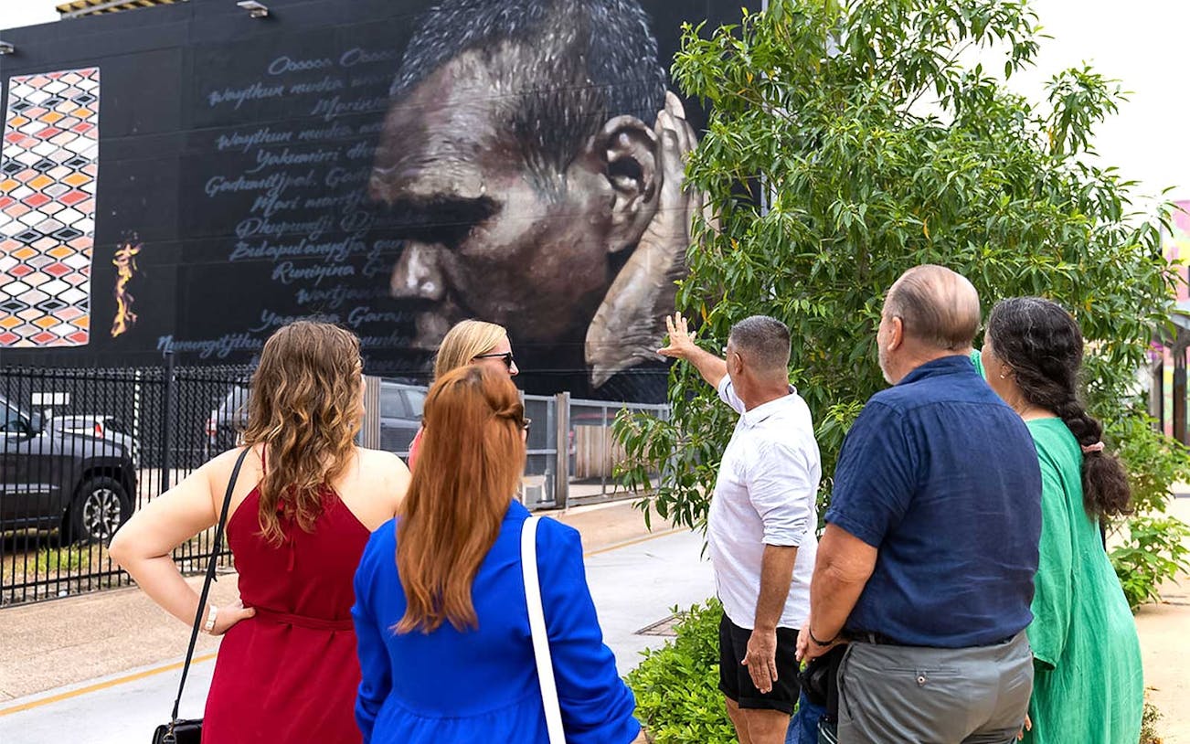 Group observing street art mural during 3.5-hour gourmet lunch or dinner and art tour.