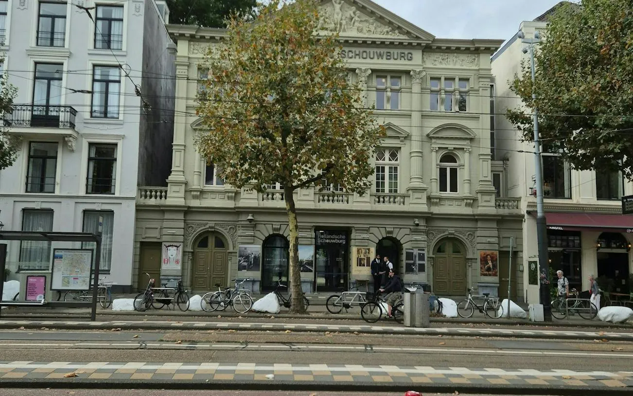 Hollandsche Schouwburg facade with bicycles and tram tracks, Amsterdam.