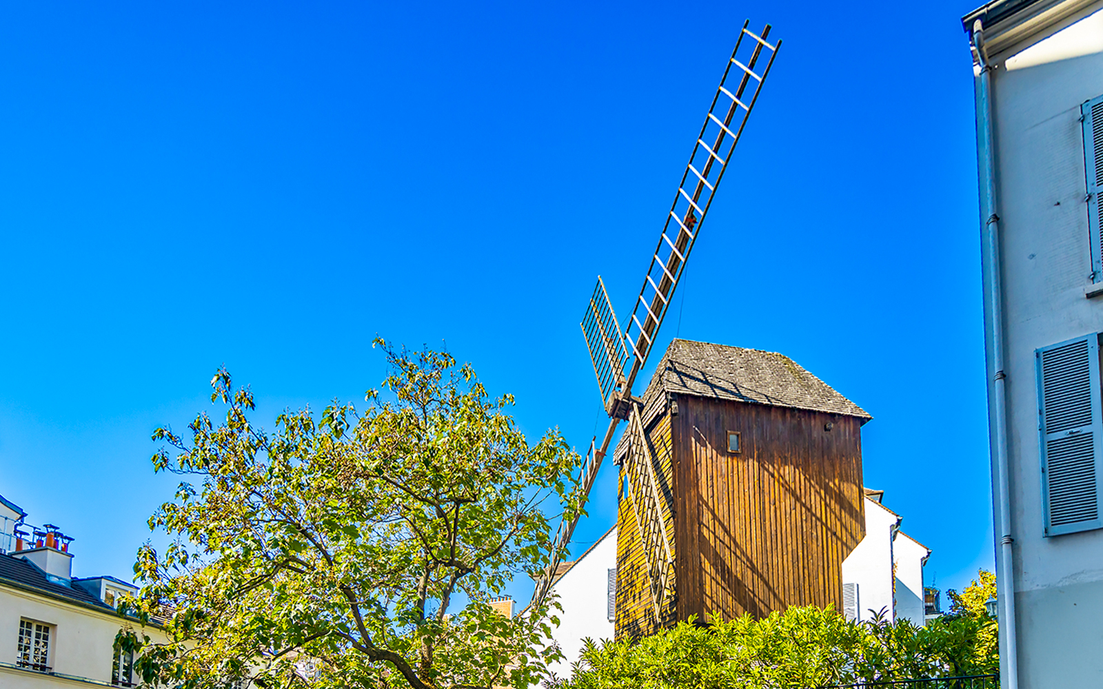 Moulin de la Galette windmill on Montmartre Hill, Paris, surrounded by trees.