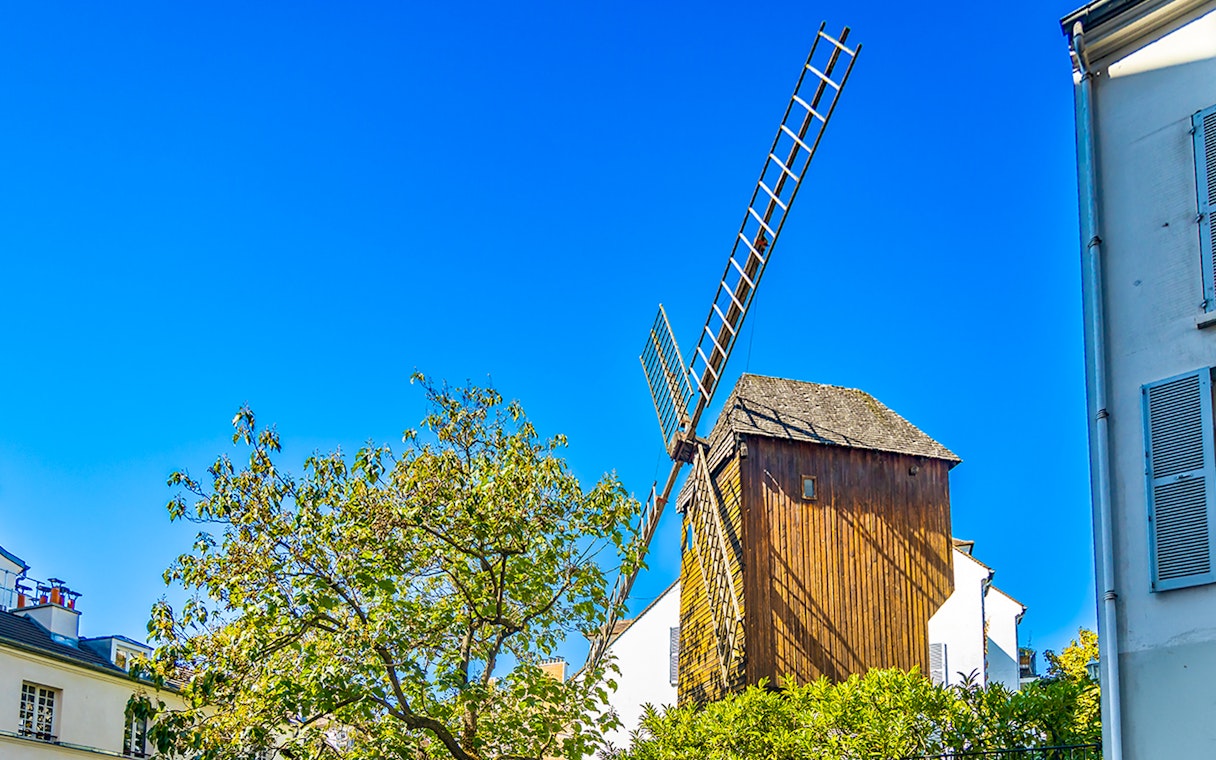 Moulin de la Galette windmill on Montmartre Hill, Paris, surrounded by trees.