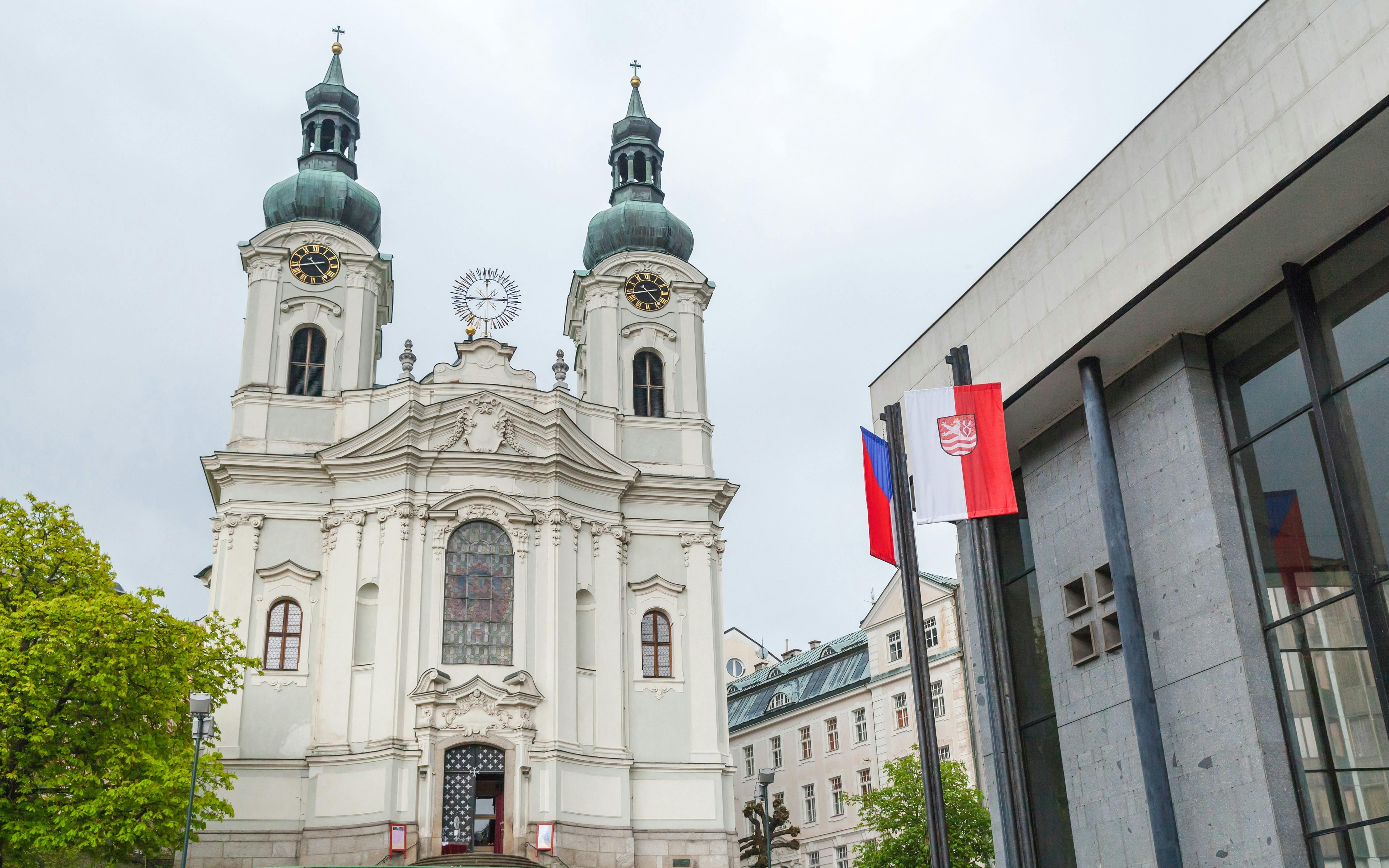 St. Mary Magdalene Church with twin towers and nearby modern building in Karlovy Vary, Czech Republic.