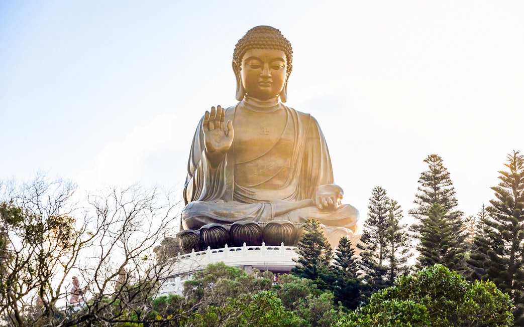 Tian Tan Buddha statue surrounded by trees on Lantau Island, Hong Kong.