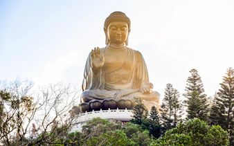 Tian Tan Buddha statue surrounded by trees on Lantau Island, Hong Kong.