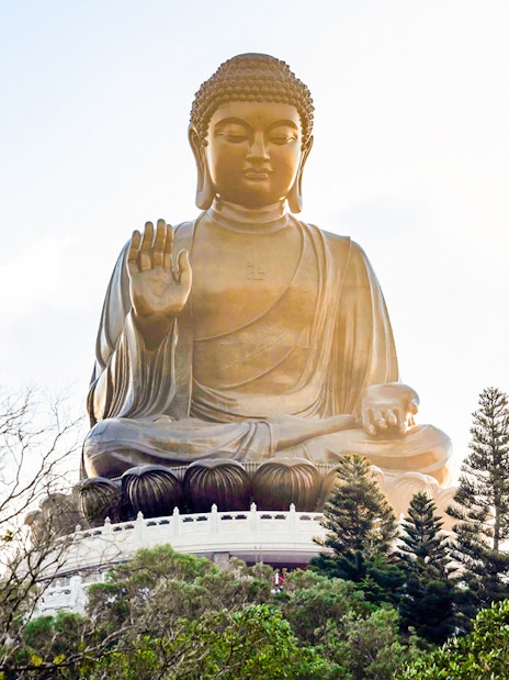 Tian Tan Buddha statue surrounded by trees on Lantau Island, Hong Kong.