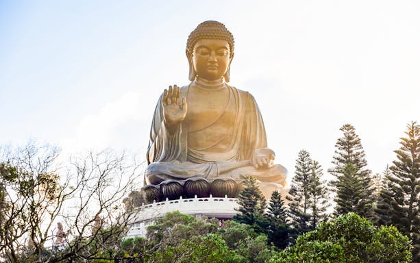 Tian Tan Buddha statue surrounded by trees on Lantau Island, Hong Kong.