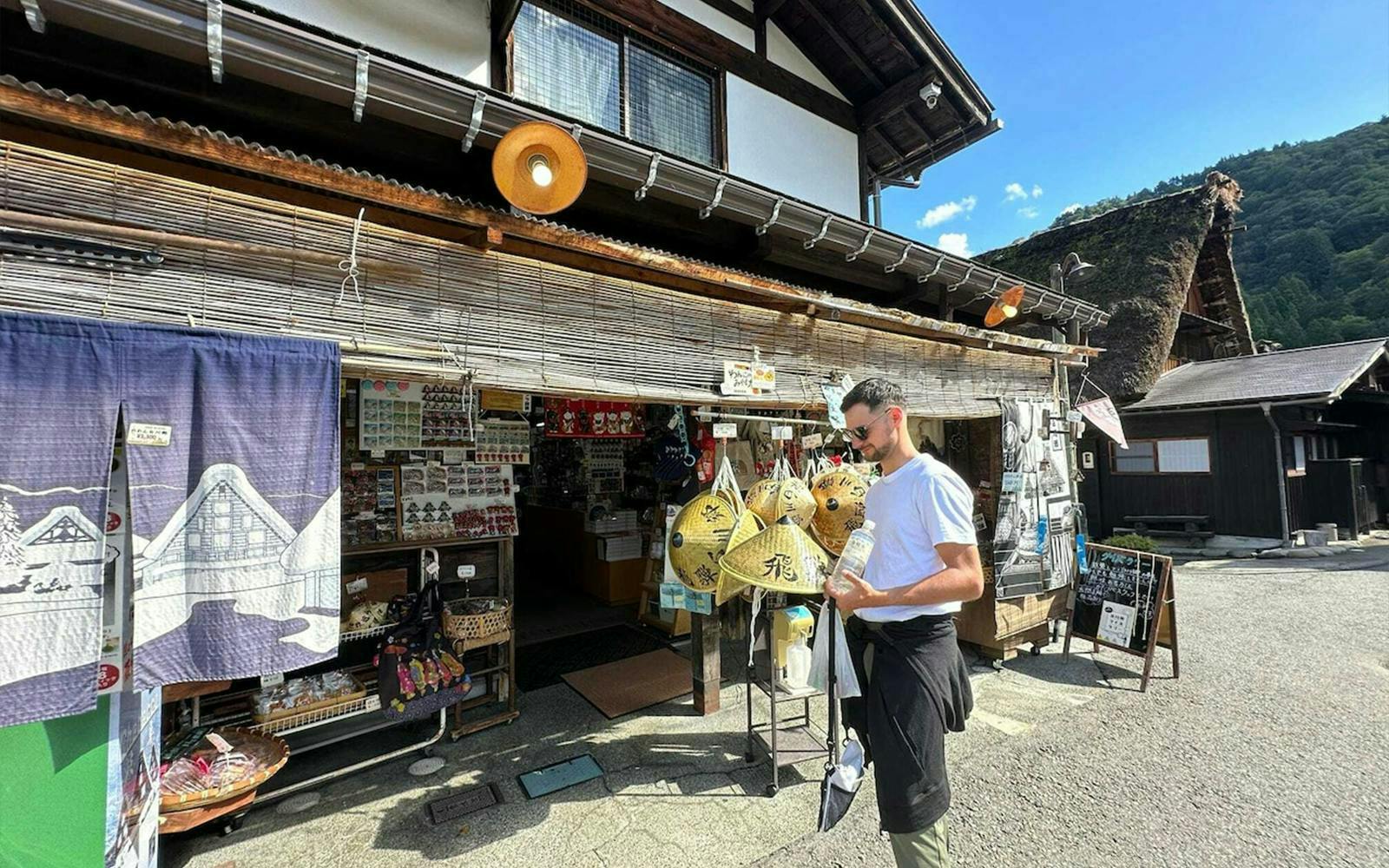 Traditional shop in Shirakawa-go with visitor browsing souvenirs, Kanazawa day tour.