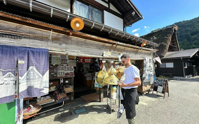Traditional shop in Shirakawa-go with visitor browsing souvenirs, Kanazawa day tour.