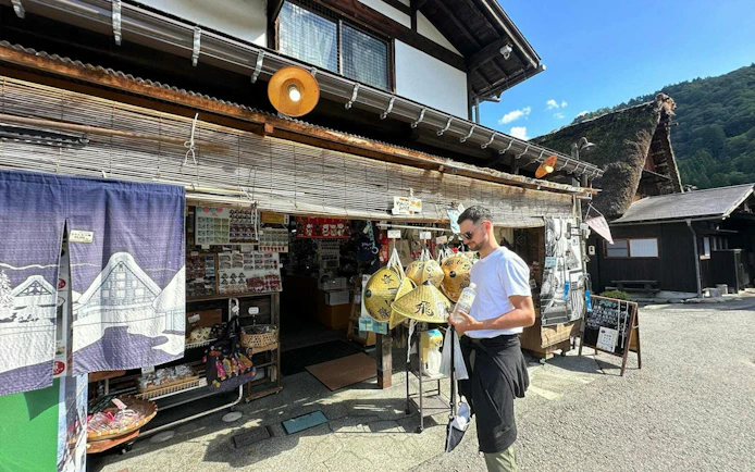 Traditional shop in Shirakawa-go with visitor browsing souvenirs, Kanazawa day tour.