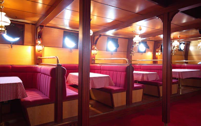 Interior of a cruise ship dining area with red booths and checkered tablecloths, Dubrovnik tour.