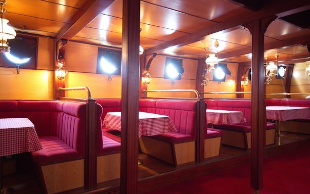 Interior of a cruise ship dining area with red booths and checkered tablecloths, Dubrovnik tour.